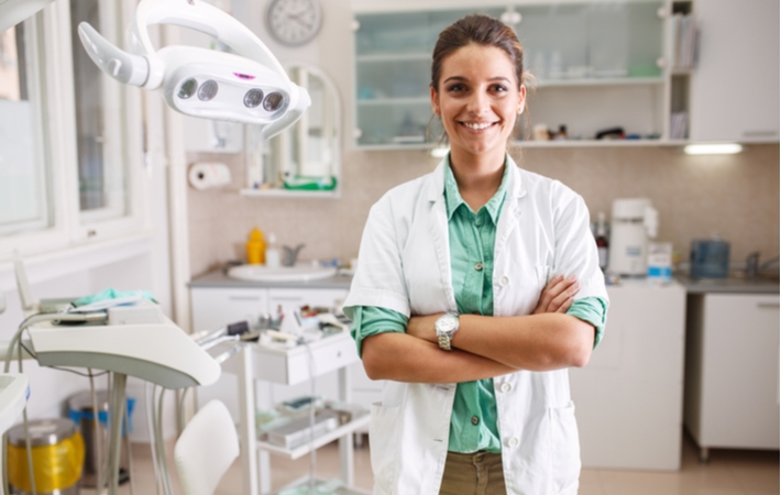 A dentist with their arms crossed smiling as her dental practice has increased performance due to a recall system